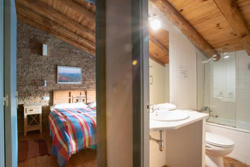 Un baño con lavabo y una cama en una habitación. en Casa de los Curas, chimenea 2 Hab 4 Pers Max, en Puerto de la Laja