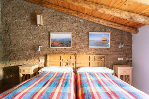 Dos camas en una habitación con pared de piedra. en Casa de los Curas, chimenea 2 Hab 4 Pers Max, en Puerto de la Laja