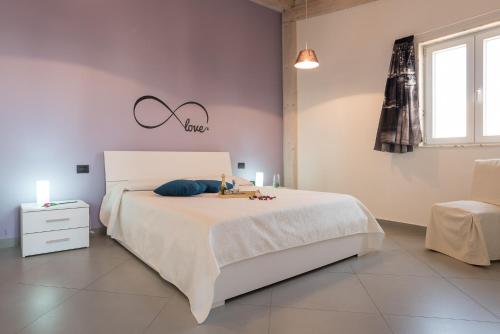 ein Schlafzimmer mit einem großen weißen Bett und einem Stuhl in der Unterkunft Casa Zefiro in Pozzallo