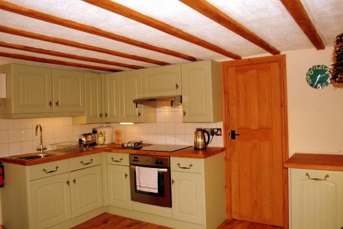 a kitchen with white cabinets and a wooden ceiling at Hillocks Cottage, Kniveton in Kniveton