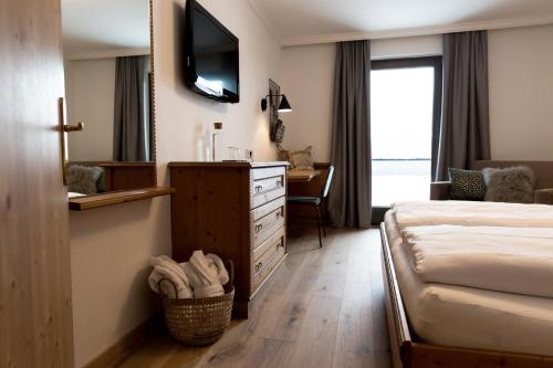 a hotel room with a bed and a dresser and a mirror at Designhotel Sonnhof by Vitus Winkler in Sankt Veit im Pongau