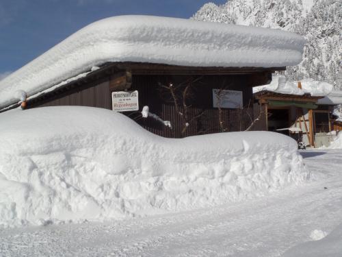 a snow covered car parked in front of a building at Haus Regenbogen in Pertisau