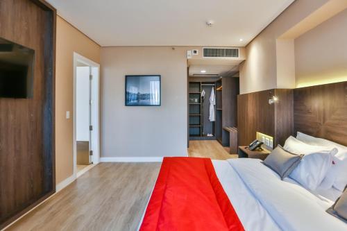a bedroom with a large bed with a red blanket at Transamerica Collection Goiania in Goiânia