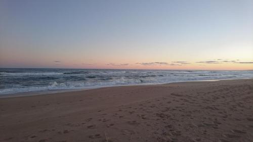 a beach with footprints in the sand and the ocean at Aloha Village in La Pedrera