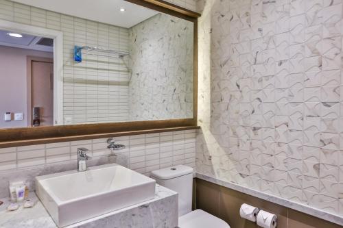 a bathroom with a sink and a toilet and a mirror at Transamerica Collection Goiania in Goiânia