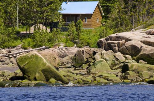 a log cabin on the shore of a river with rocks at Centre de Vacances 5 Étoiles Family Resort in Sacré-Coeur-Saguenay
