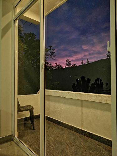 a sliding glass door with a chair in front of a window at Heaven Hills Guest House in Maskeliya