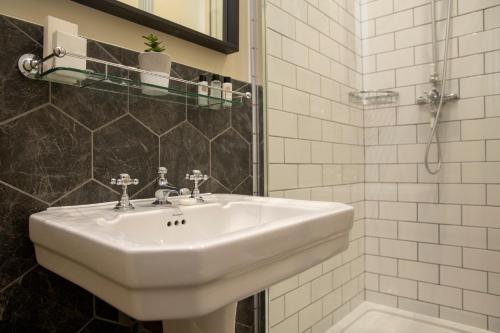 a bathroom with a white sink and a shower at The Princess Victoria in London
