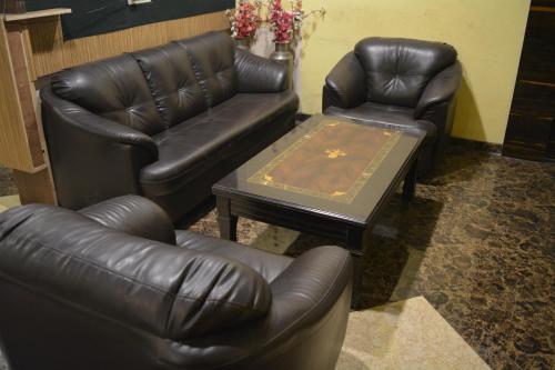 a living room with leather furniture and a coffee table at Dhuri Resort in Vasai