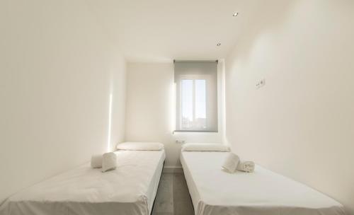 two beds in a white room with a window at SohoSuites Villavieja in Alicante