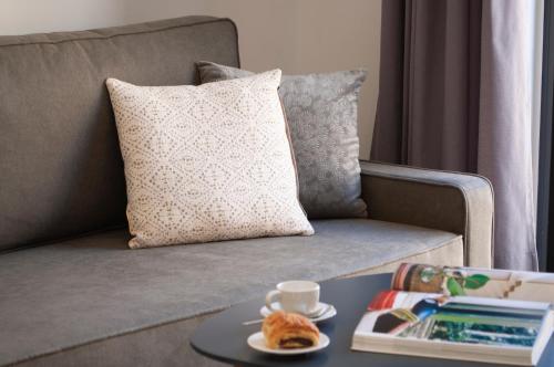 a couch with a pillow and a table with a cup of coffee at SohoSuites Villavieja in Alicante