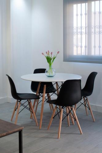 a table with four chairs and a vase with flowers on it at SohoSuites Villavieja in Alicante