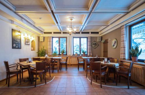 uma sala de jantar com mesas, cadeiras e janelas em Hotel Aquamarin em Bad Mitterndorf