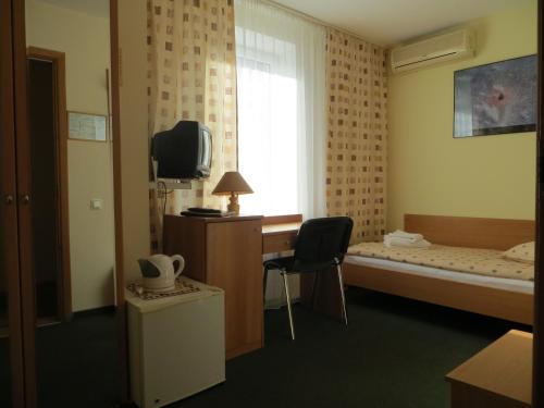 サマラにあるKorona Hotelのベッド、デスク、テレビが備わるホテルルームです。