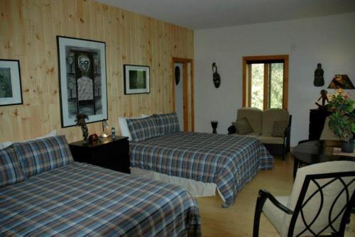 a bedroom with two beds and a table and a chair at Gîte au Pied du Courant de Gilbert Desjardins in Mont-Laurier