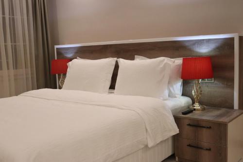 Yankı Hotel في Çekirge: سرير بمخدات بيضاء ومصباح احمر على الموقف الليلي