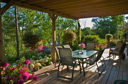 a patio with a table and chairs and flowers at Gîte au Pied du Courant de Gilbert Desjardins in Mont-Laurier