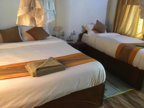 two beds in a hotel room with acknowled at Rhino Lodge Bardia Pvt Ltd in Bhurkīā