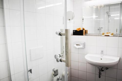 a white bathroom with a sink and a shower at Anor Hotel & Conference Center Frankfurt Airport in Mörfelden-Walldorf
