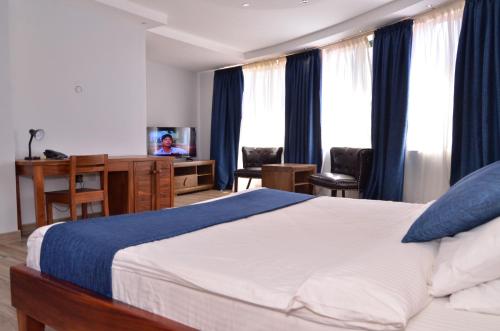a bedroom with a large bed with blue curtains at Nile Village Hotel & Spa in Jinja
