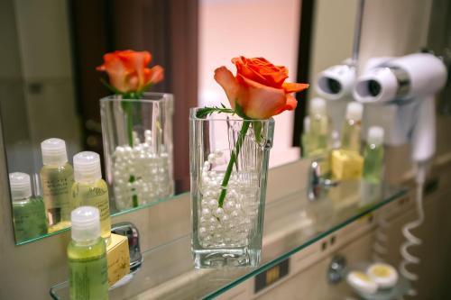 a vase with a rose in it on a bathroom counter at Edem Hotel Lviv in Lviv