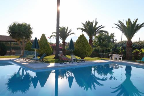 a person sitting in a chair next to a swimming pool at Regina Hotel in Kissamos