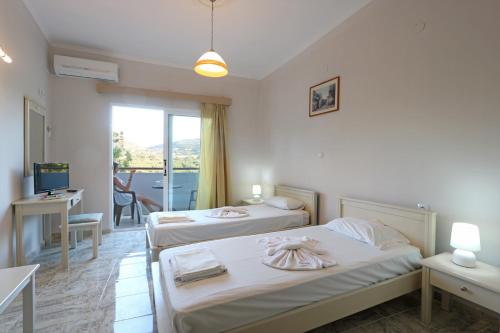 a bedroom with two beds and a desk and a window at Regina Hotel in Kissamos