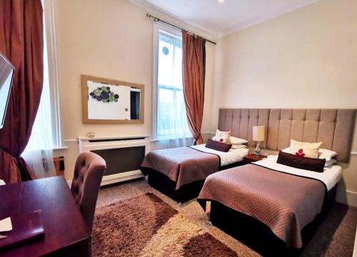 um quarto de hotel com duas camas e uma mesa em Rushmore Hotel em Londres