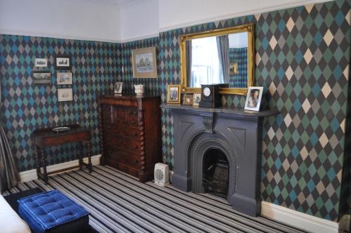 a living room with a fireplace and green and white wallpaper at Aberley House in Liverpool