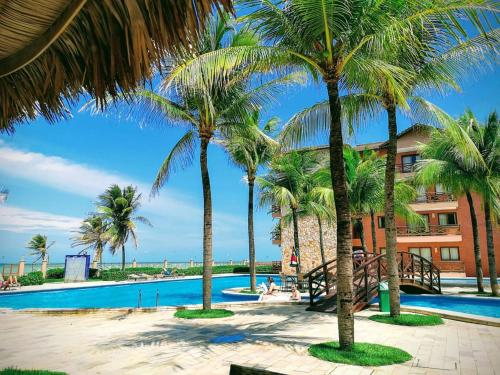 een resort met een zwembad en palmbomen bij Kariri Apartaments Sunset Beach in Cumbuco