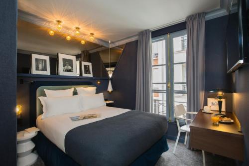 a hotel room with a bed and a desk and a window at Bob Hotel in Paris