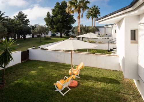 a yard with two chairs and an umbrella at Parador de Ayamonte in Ayamonte