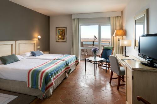 een hotelkamer met een bed, een bureau en een televisie bij Parador de Ayamonte in Ayamonte