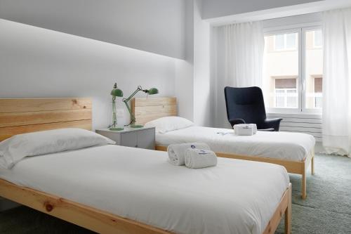 Duas camas num quarto com uma cadeira e uma cadeira em Kimu - Basque Stay em San Sebastián