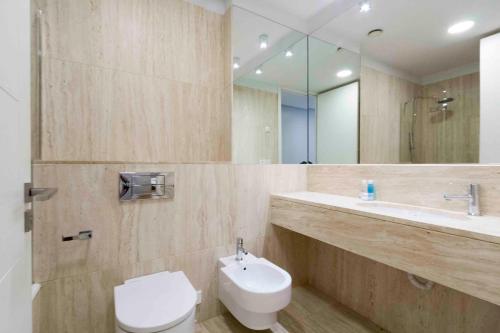 een badkamer met een toilet, een wastafel en een spiegel bij The Rentals Collection | Alday in San Sebastian