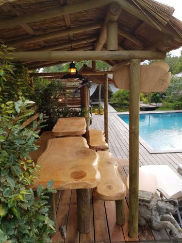 a wooden pergola with benches on a deck next to a pool at la Varangue in Lacanau