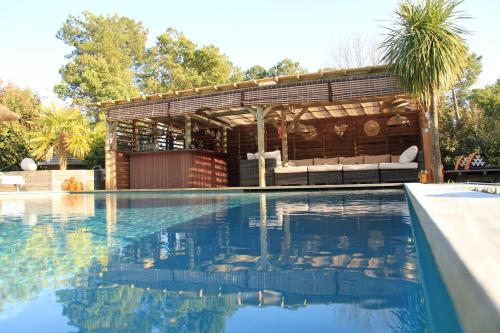 a swimming pool with a pergola next to a house at la Varangue in Lacanau