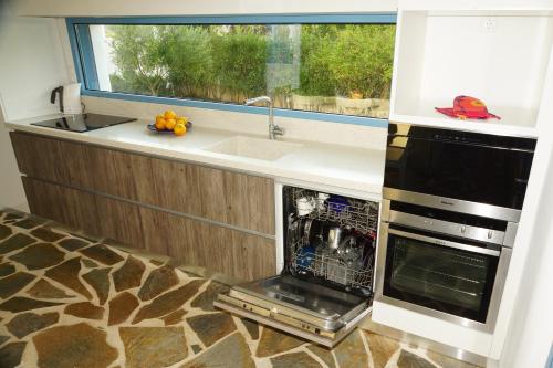 a kitchen with a dishwasher and a sink and a window at Villa in Marathonos in Schinias