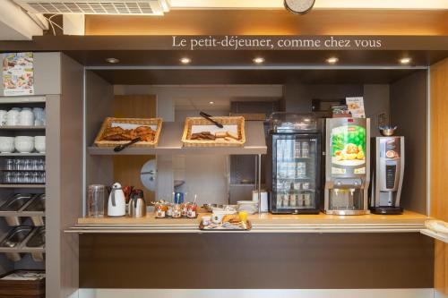 a coffee shop with a counter with a refrigerator at B&B HOTEL Herblay in Herblay