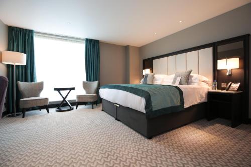 a hotel room with a bed and two chairs at Grand Central Hotel Belfast in Belfast