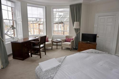a hotel room with a bed and a desk and chairs at Bank House in King's Lynn