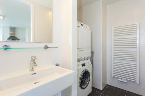 a white bathroom with a sink and a washing machine at Buitenplaats Witte Raaf aan Zee in Noordwijk