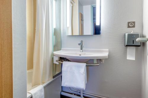 a bathroom with a sink and a mirror and a towel at B&B HOTEL Orgeval in Orgeval