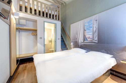 B&B HOTEL Orgeval في أورغيفال: غرفة نوم بسرير ابيض ودرج