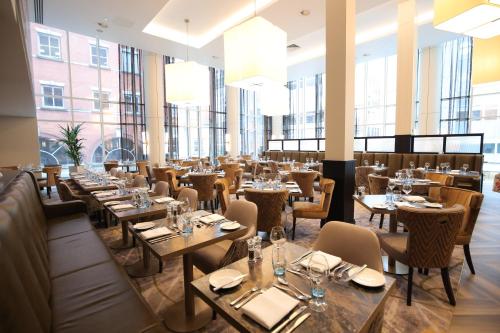 a restaurant with tables and chairs and windows at Grand Central Hotel Belfast in Belfast