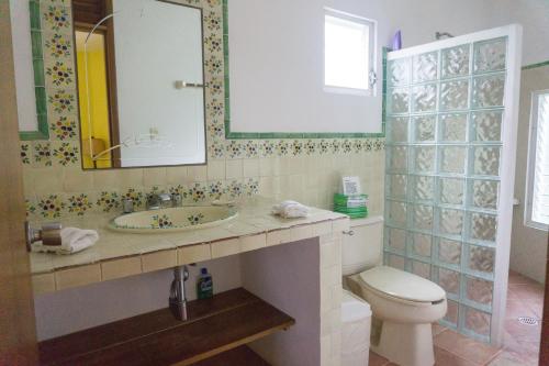 a bathroom with a sink and a toilet and a mirror at Sea Hawk Suites in Isla Mujeres
