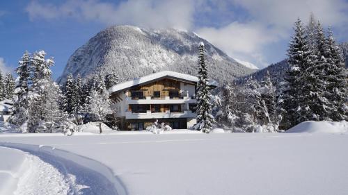 a building in the snow in front of a mountain at AKTIV Apartments in Leutasch