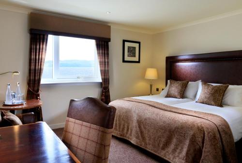Una habitación de hotel con una cama, un escritorio y una ventana. en Macdonald Aviemore Hotel at Macdonald Aviemore Resort, en Aviemore
