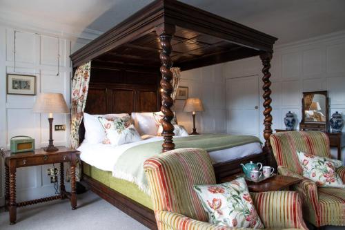 a bedroom with a canopy bed and two chairs at Spread Eagle Hotel And Spa in Midhurst