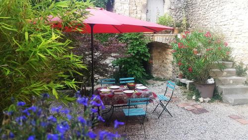 a table and chairs with an umbrella in a garden at B&B Champdelaplume in Barjac